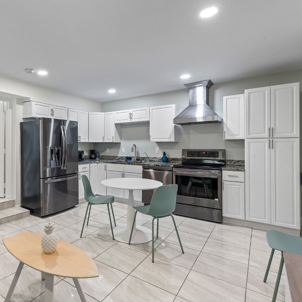 Condo full kitchen at Atlantic Shores Motel in Daytona Beach with stainless steel appliances, dining table, and modern coastal design.