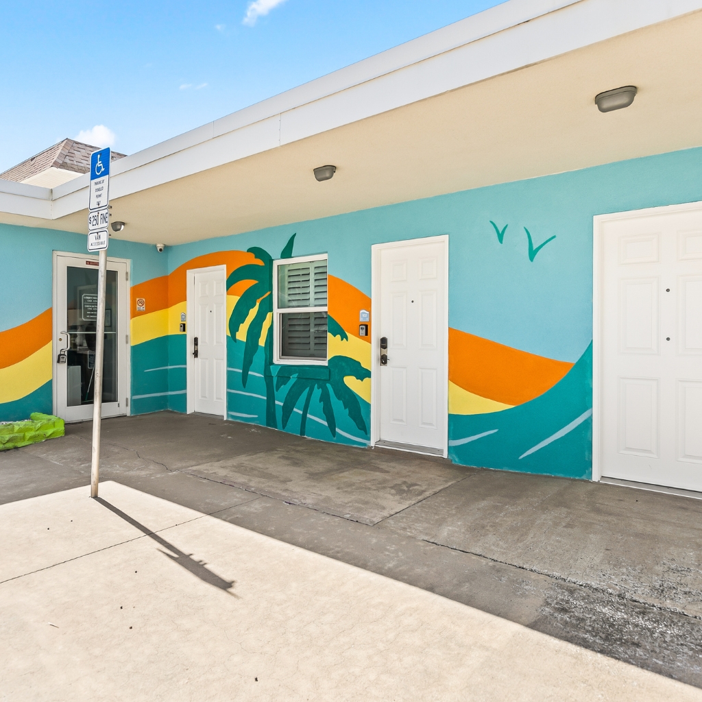 Front view of Atlantic Shores Motel in Daytona Beach featuring a colorful artistic mural on the building’s exterior wall.